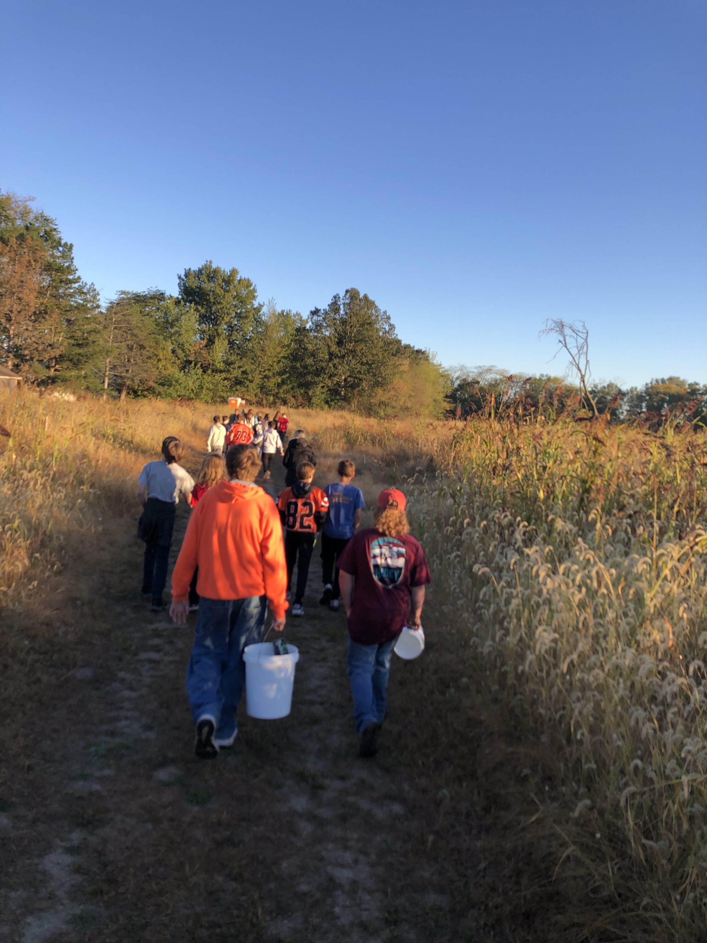 7th grade students walking from Tontagony Creek, carrying their water quality monitoring tools